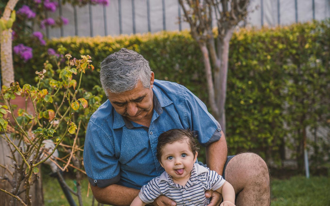 man in blue button up shirt carrying baby in black and white stripe shirt by Alvaro Reyes courtesy of Unsplash.