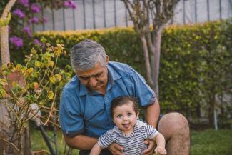 man in blue button up shirt carrying baby in black and white stripe shirt by Alvaro Reyes courtesy of Unsplash.